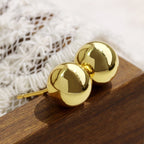 angled pair of smooth gold plated ball stud earrings