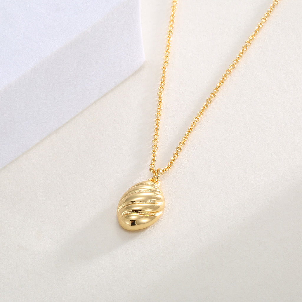 gold plated textured oval pendant hanging from a fine chain