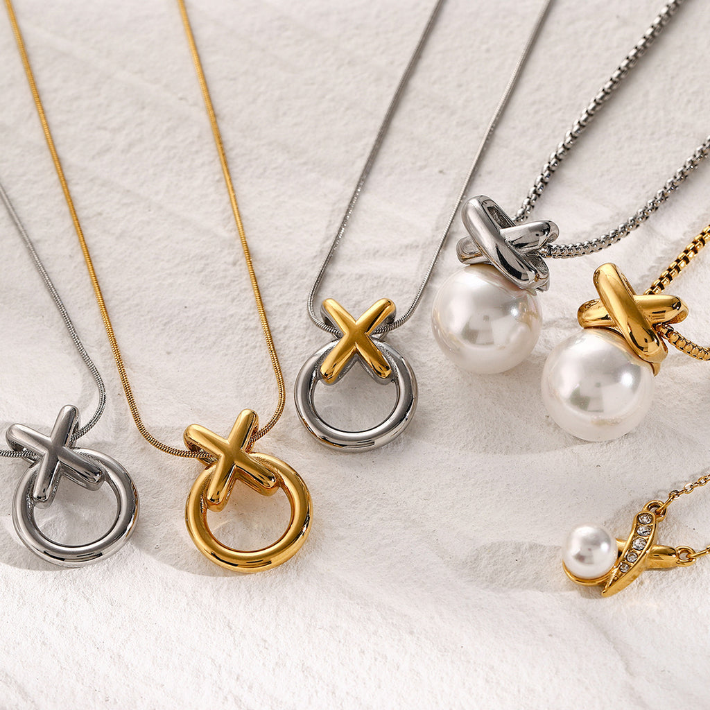 Gold- and silver-finish XO necklaces arranged on pale fabric
