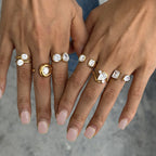 Close-up of varied clear stone settings on two hands
