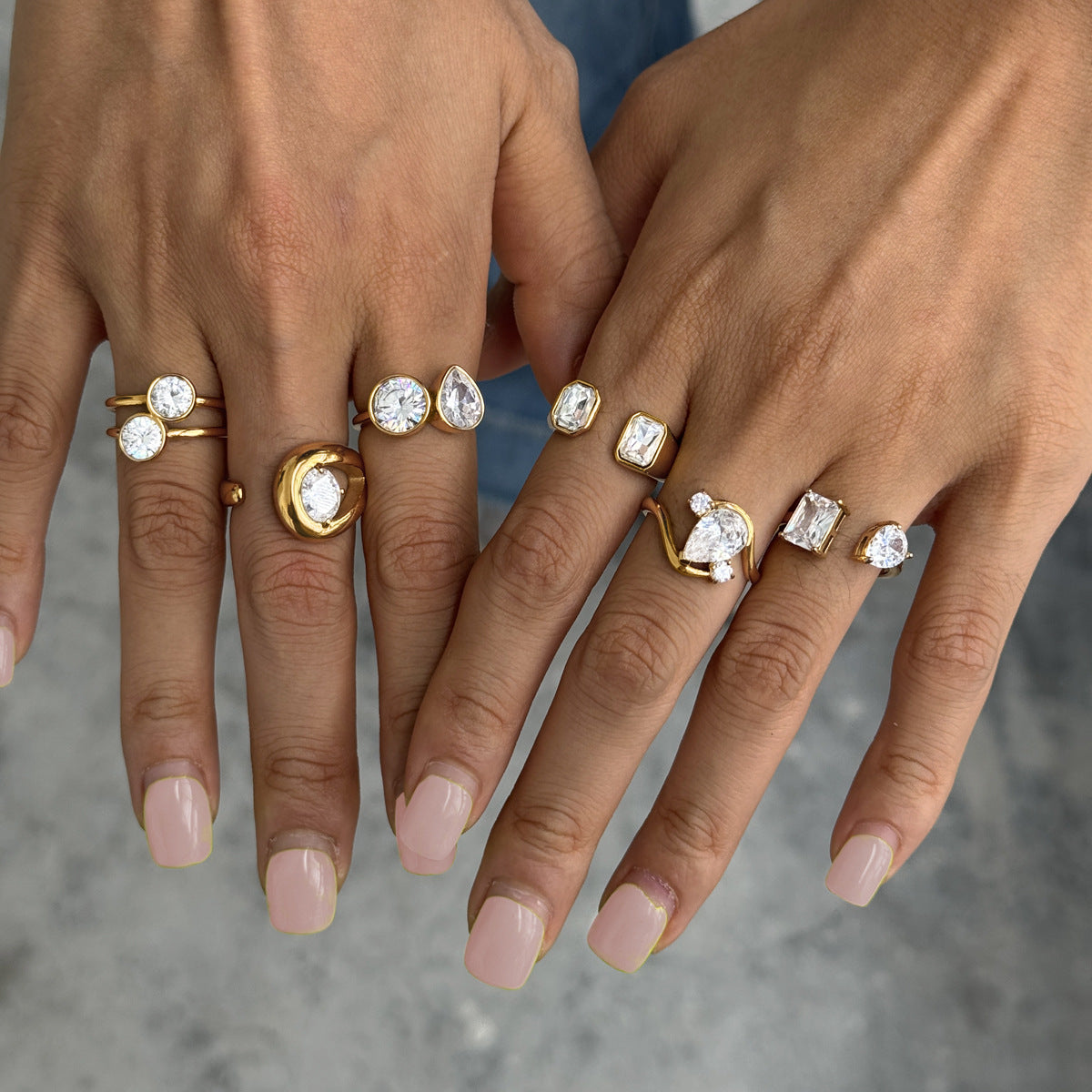Close-up of varied clear stone settings on two hands