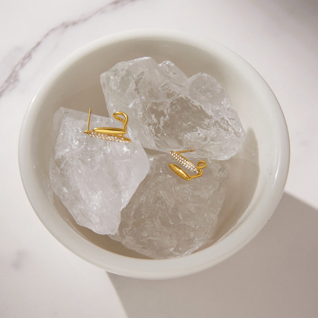 Clear stone earrings arranged on decorative white stones