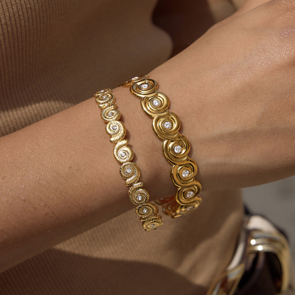 Fine and broad spiral-disc cuffs worn together