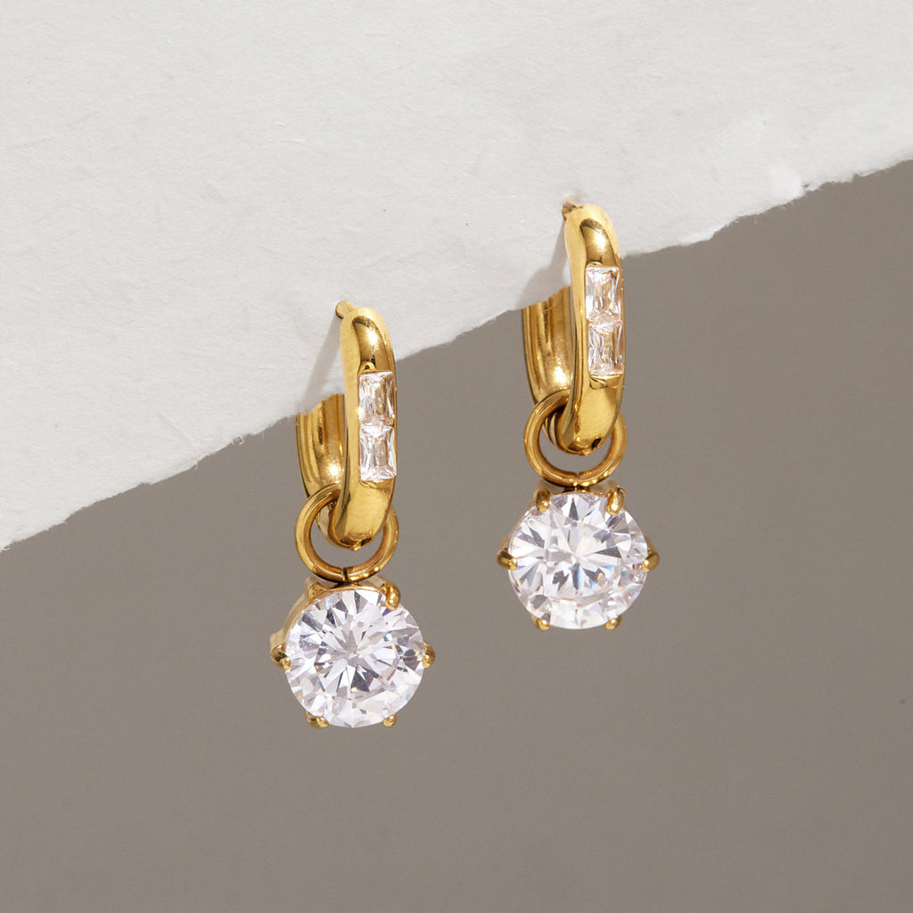 Oval hoops with round zirconia drops hanging from a ledge