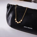 Clear stone station necklace displayed on a black bag