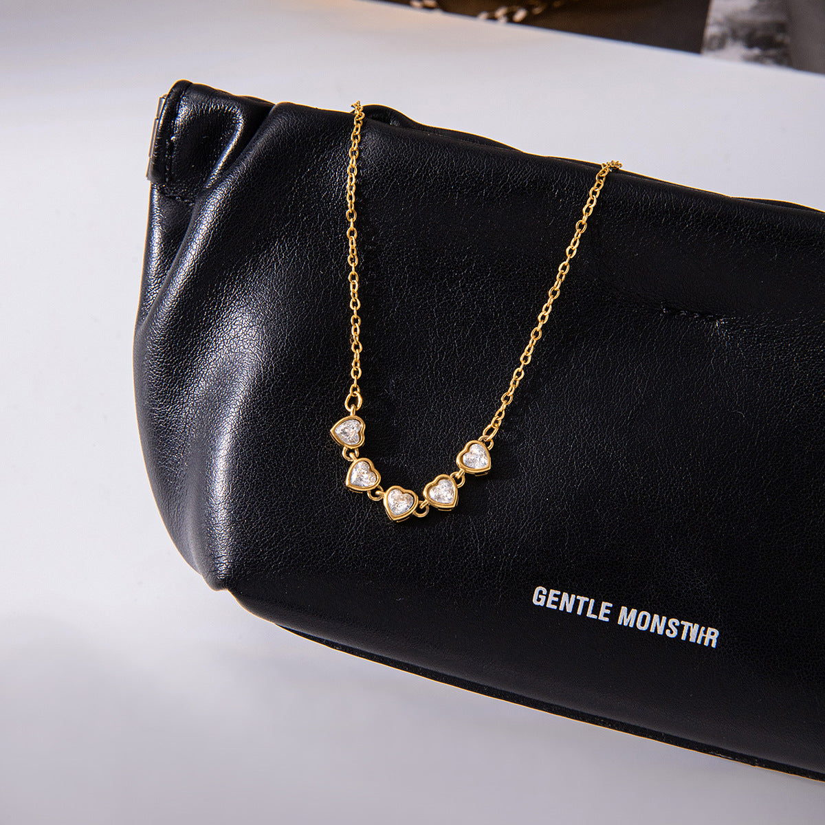 Clear stone station necklace displayed on a black bag