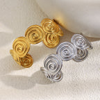 Gold plated and silver-color spiral disc cuffs on a textured display
