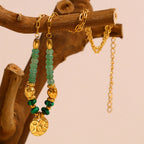 gold plated green stone bead necklace hanging from a wooden branch