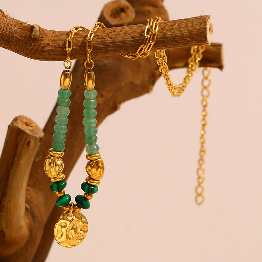 gold plated green stone bead necklace hanging from a wooden branch
