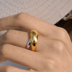 Gold-tone dome above steel-color band on a hand
