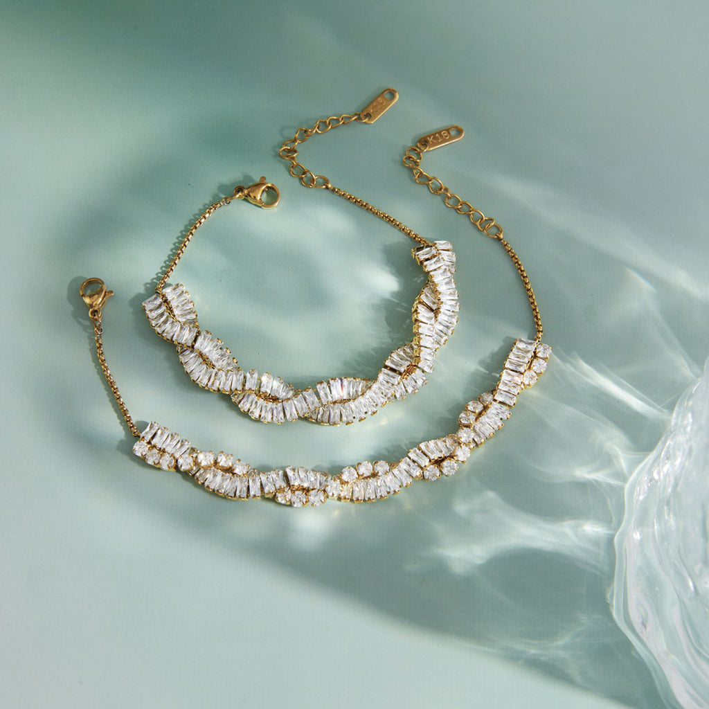 Gold-tone wave bracelets on a pale green surface