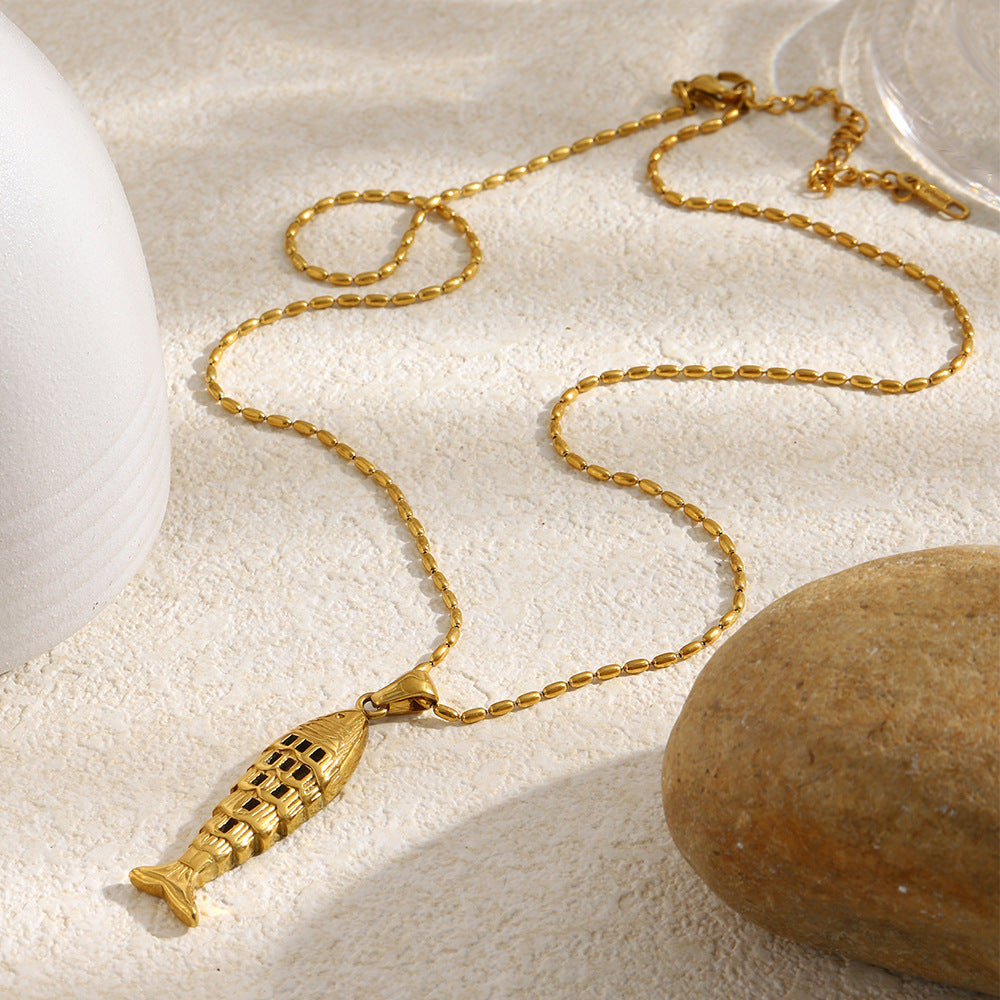 gold plated chain laid out with an elongated openwork fish pendant