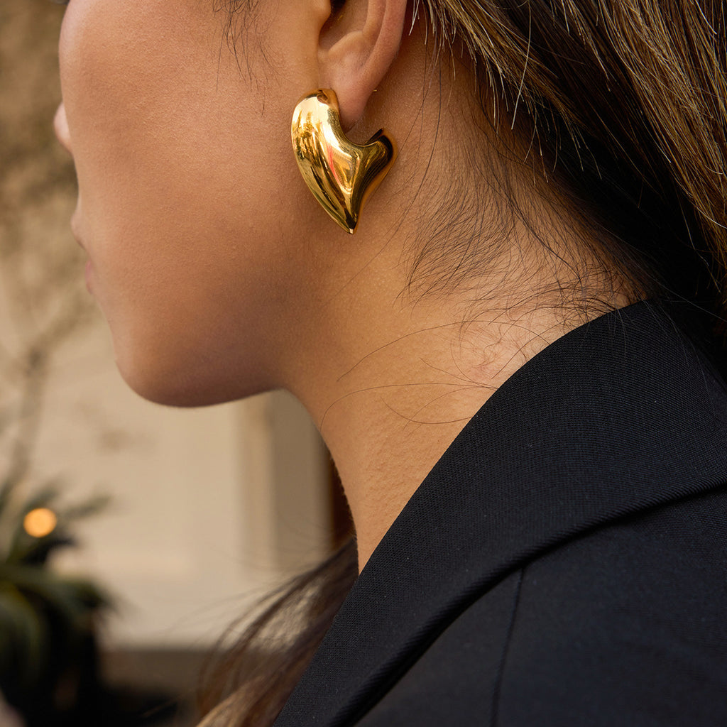 Gold-tone asymmetric sculptural heart stainless steel stud earrings worn view