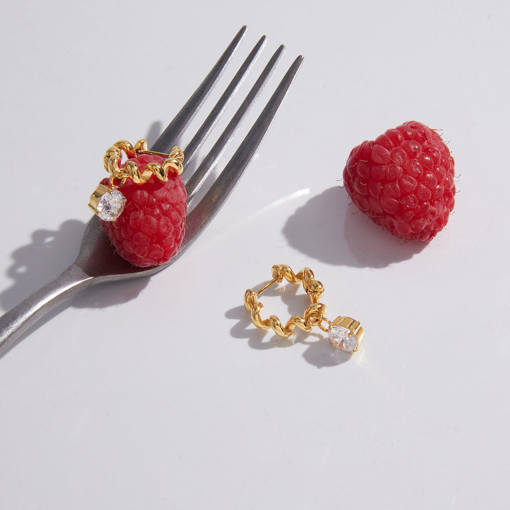 Gold-tone twisted hoops displayed with fruit