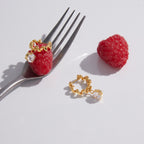 Gold-tone twisted hoops displayed with fruit
