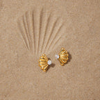 Gold finish fan earrings arranged on sand