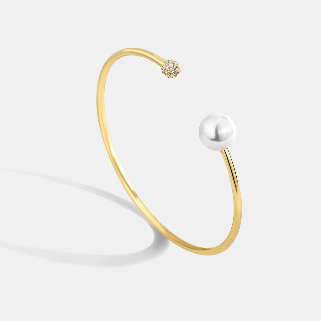 gold plated open bangle with pearl-style bead and clear stone cluster