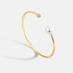 gold plated open bangle with pearl-style bead and clear stone cluster