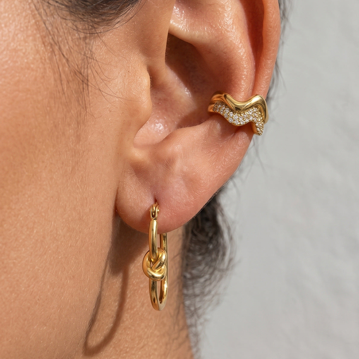 Gold tone knot hoop and wavy ear cuff worn together