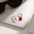 asymmetric heart and beaded huggie earrings styled on a desk