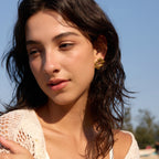 Gold-tone floral studs shown on a model
