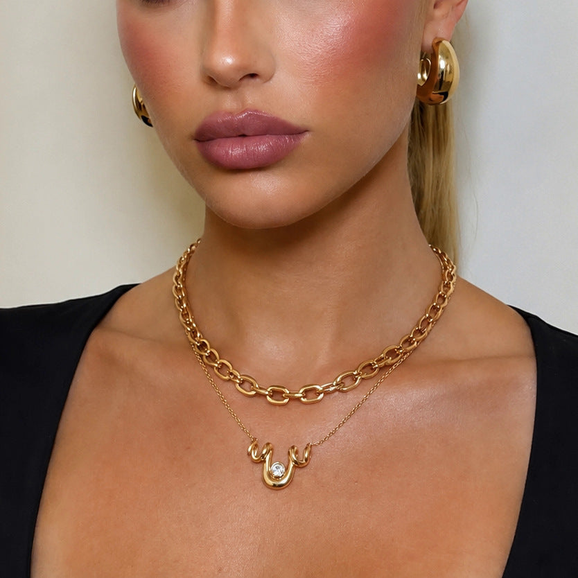 Wave pendant necklace layered with a plain oval-link chain