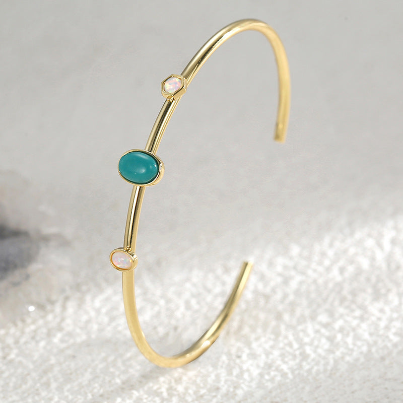 slim turquoise-color stone cuff standing on a textured surface