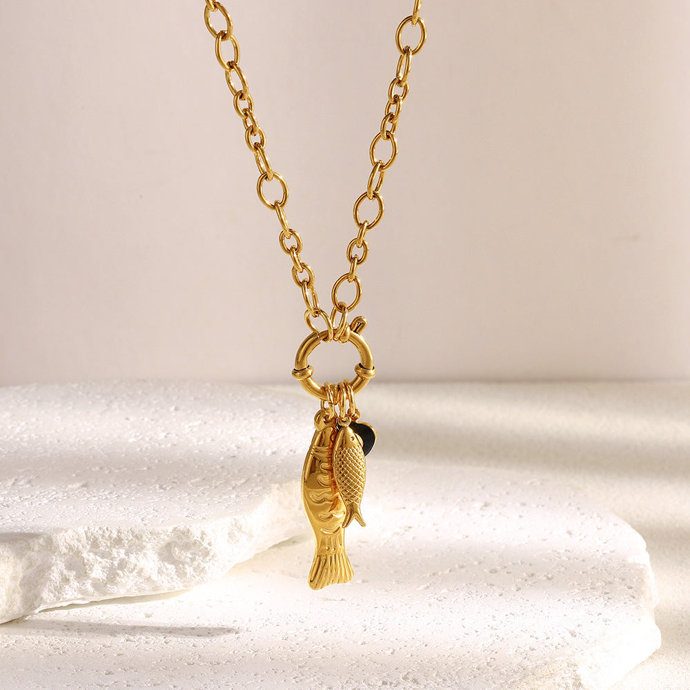 gold plated stainless steel fish necklace arranged on satin