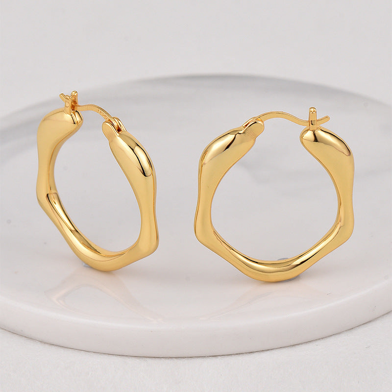 gold plated wavy oval hoop earrings on a white display
