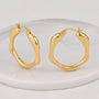 gold plated wavy oval hoop earrings on a white display