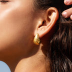 Textured gold-tone teardrop stud worn close-up