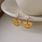 Pair of heart medallion drops displayed beside a cup