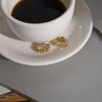 Pair of twisted link hoops displayed beside a cup