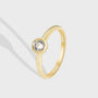 isolated gold plated brass ring with round bezel-set clear stone