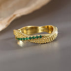 front view of green-stone ring between textured crossing bands