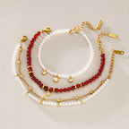 Three red and white beaded bracelet options arranged on stone