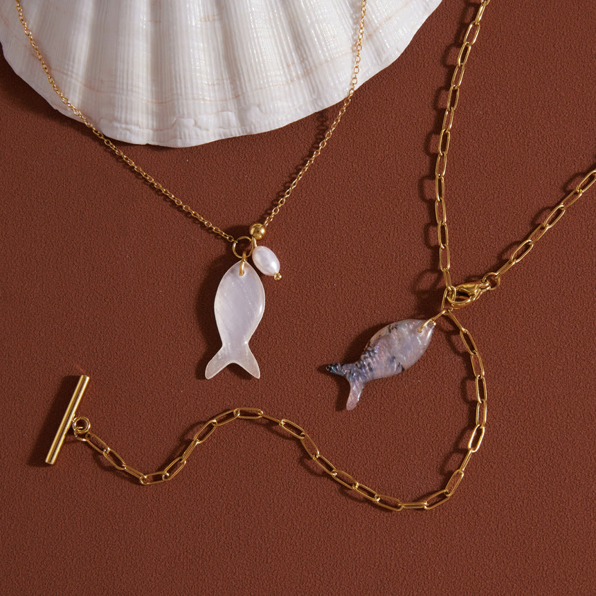 Fish necklaces displayed beside a large shell