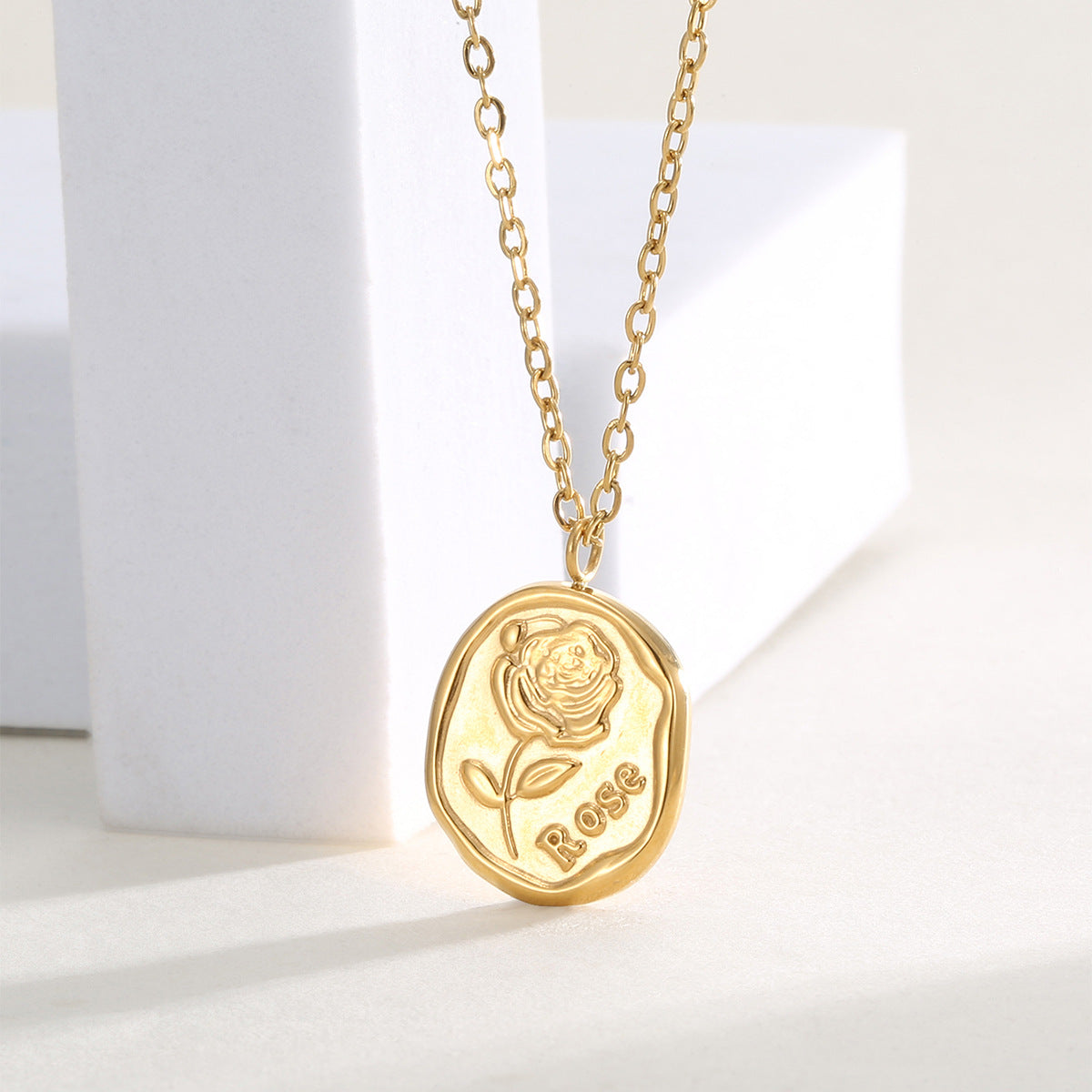angled view of the raised rose relief pendant and fine chain