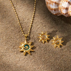 Sun pendant and earrings displayed on sand