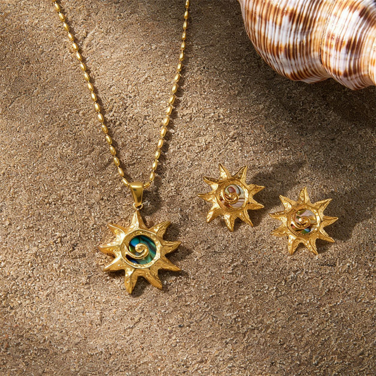 Sun pendant and earrings displayed on sand