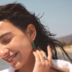Green striped oval accent hoop earrings shown on a model