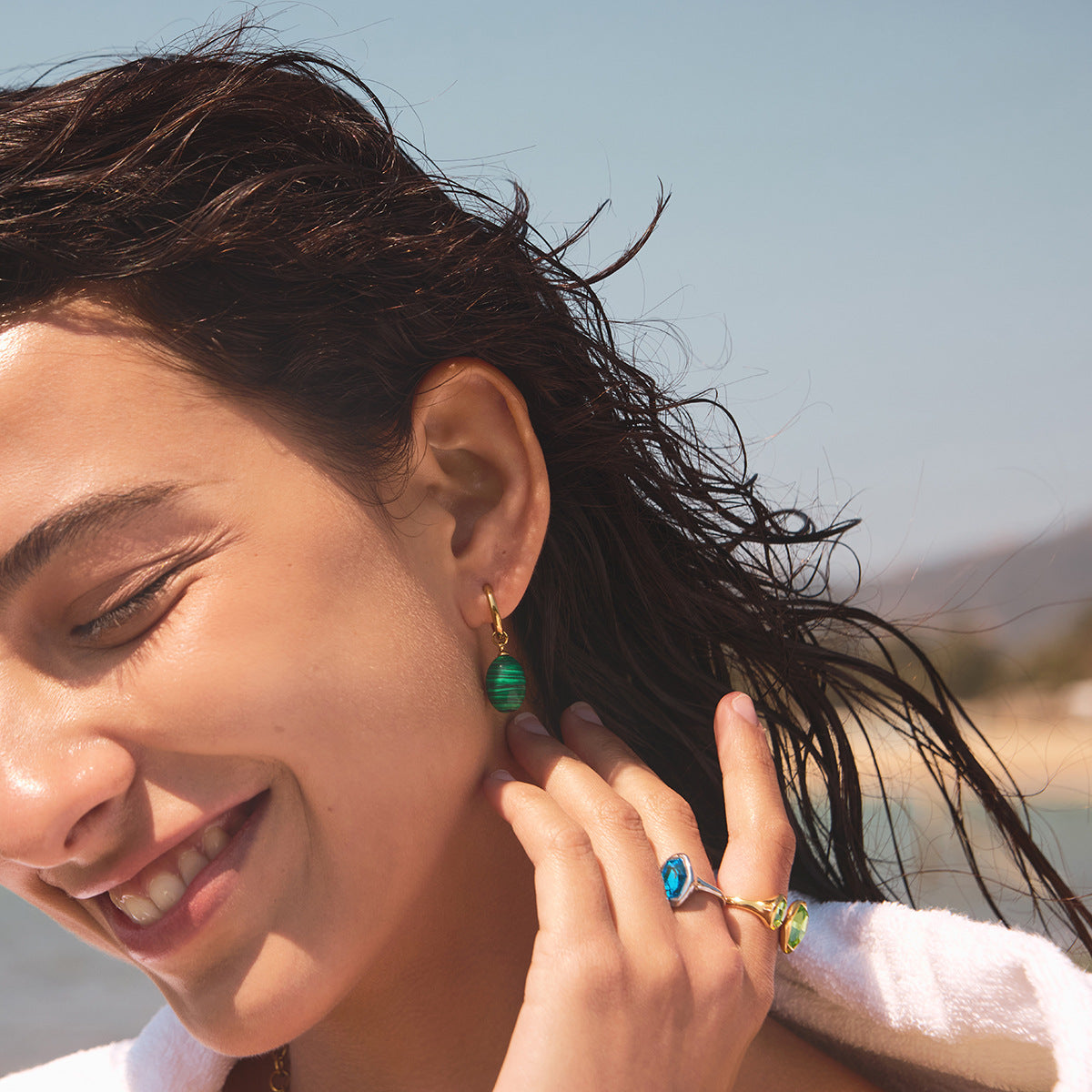 Green striped oval accent hoop earrings shown on a model