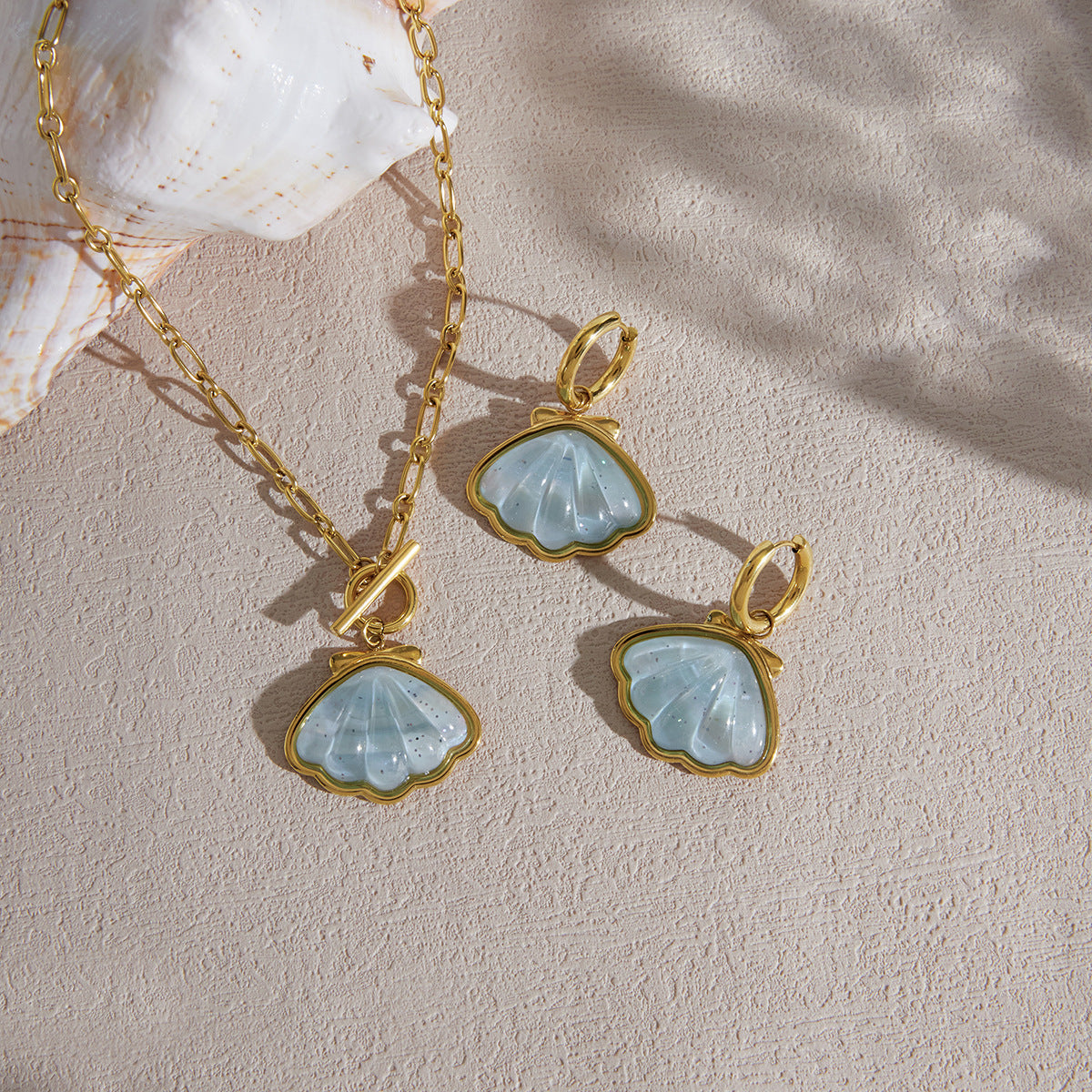 Blue shell jewelry displayed on fabric beside a shell