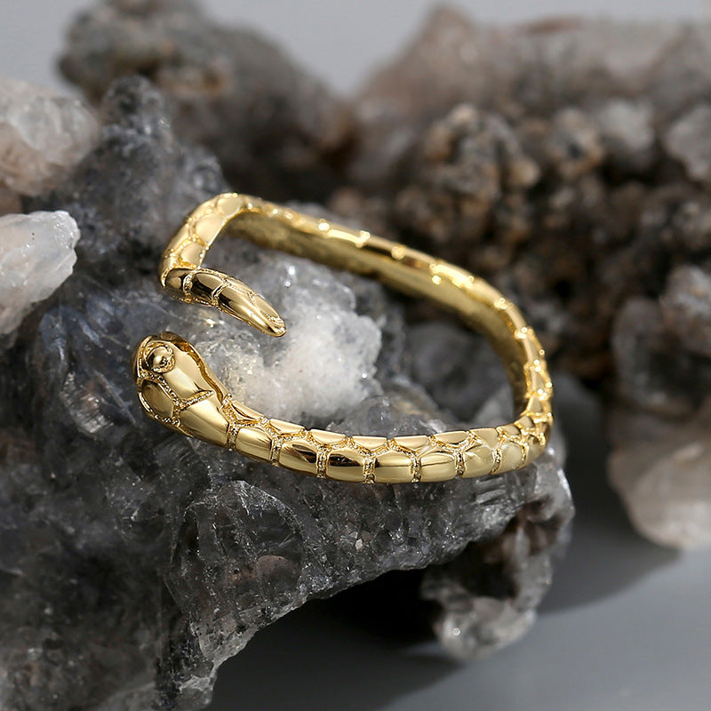 snake ring resting on a dark mineral with sculpted head visible