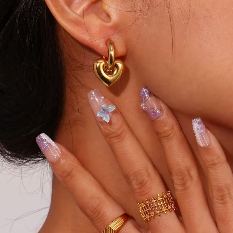 Gold heart drop hoop earring worn close-up