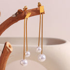 gold plated double-chain imitation pearl drop earrings on a wood branch