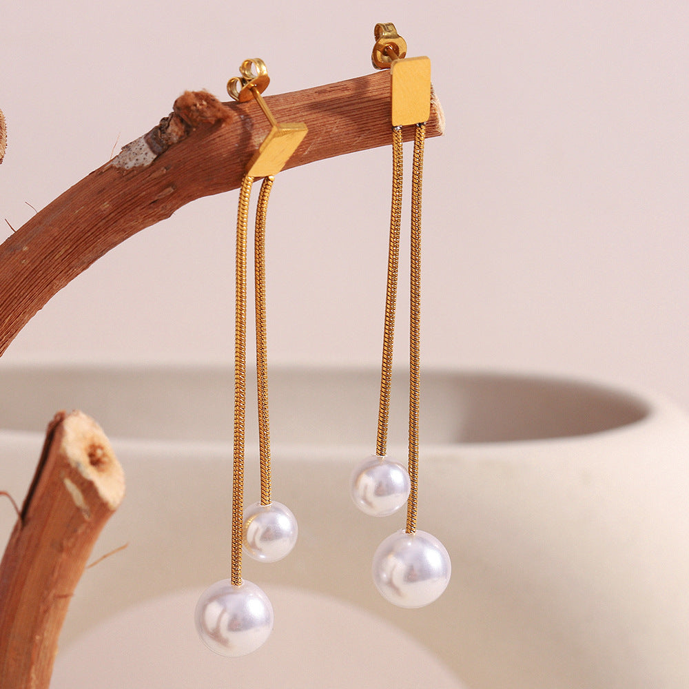 gold plated double-chain imitation pearl drop earrings on a wood branch