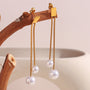 gold plated double-chain imitation pearl drop earrings on a wood branch