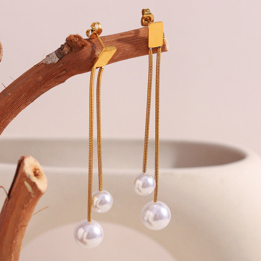 gold plated double-chain imitation pearl drop earrings on a wood branch
