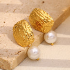 hammered gold and white pearl earrings on a beige stone block